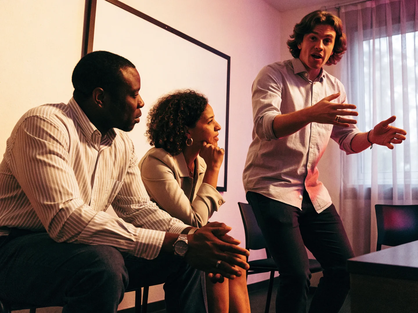 Three adult organizers discuss their approach beside a blank board