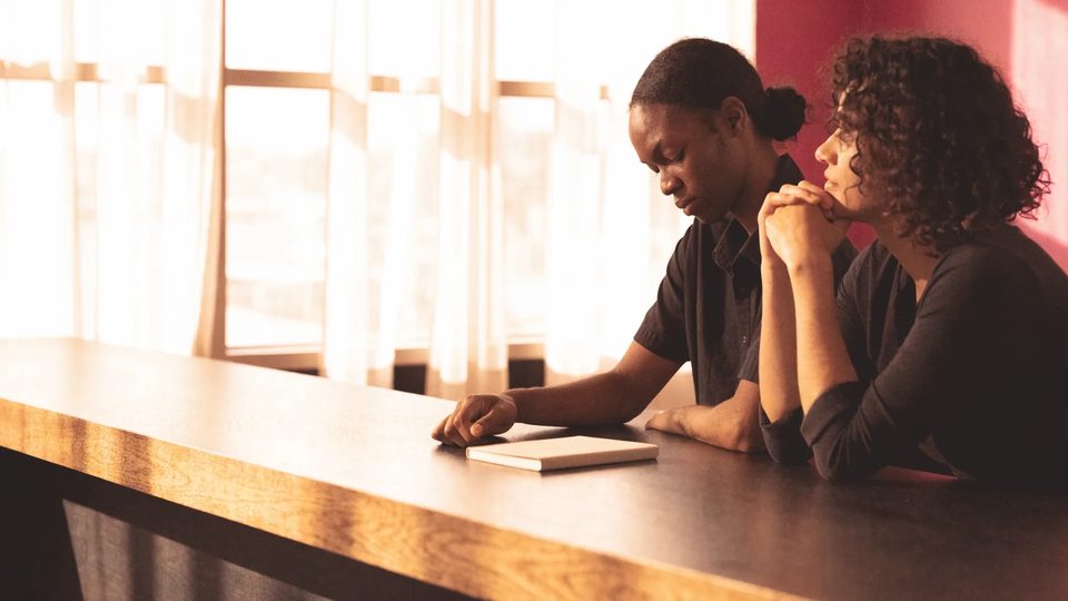 Two venue managers planning at a sunlit bar counter.