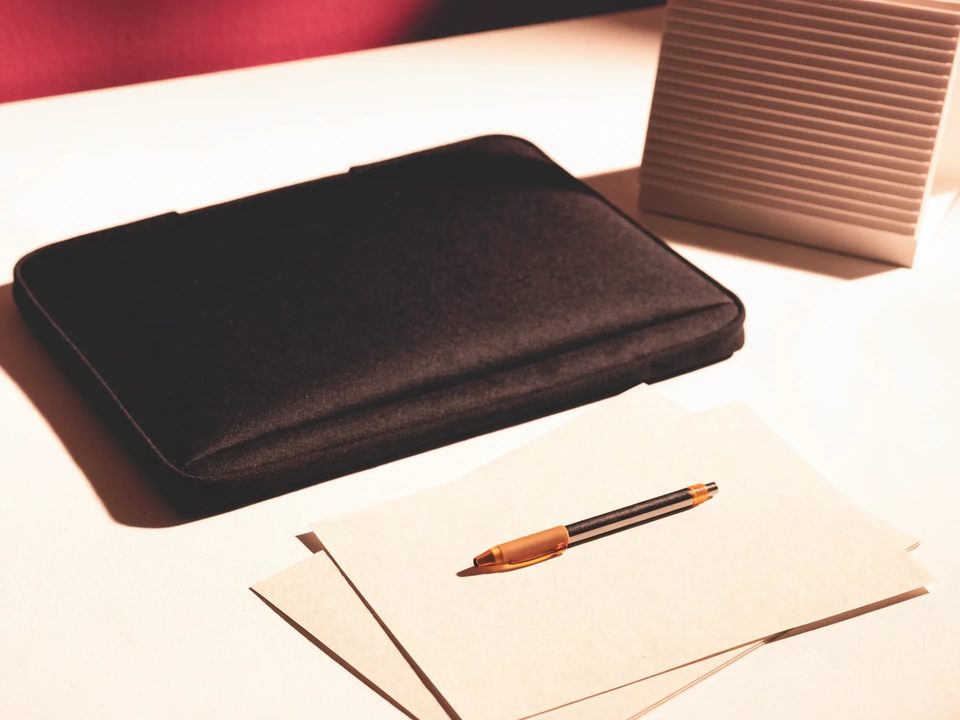 Blank papers, a covered laptop, a numberless desk calendar and a pen.